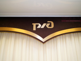 Фрагмент тематического гладкого ламбрекена с аппликацией логотипа РЖД для офисного помещения.