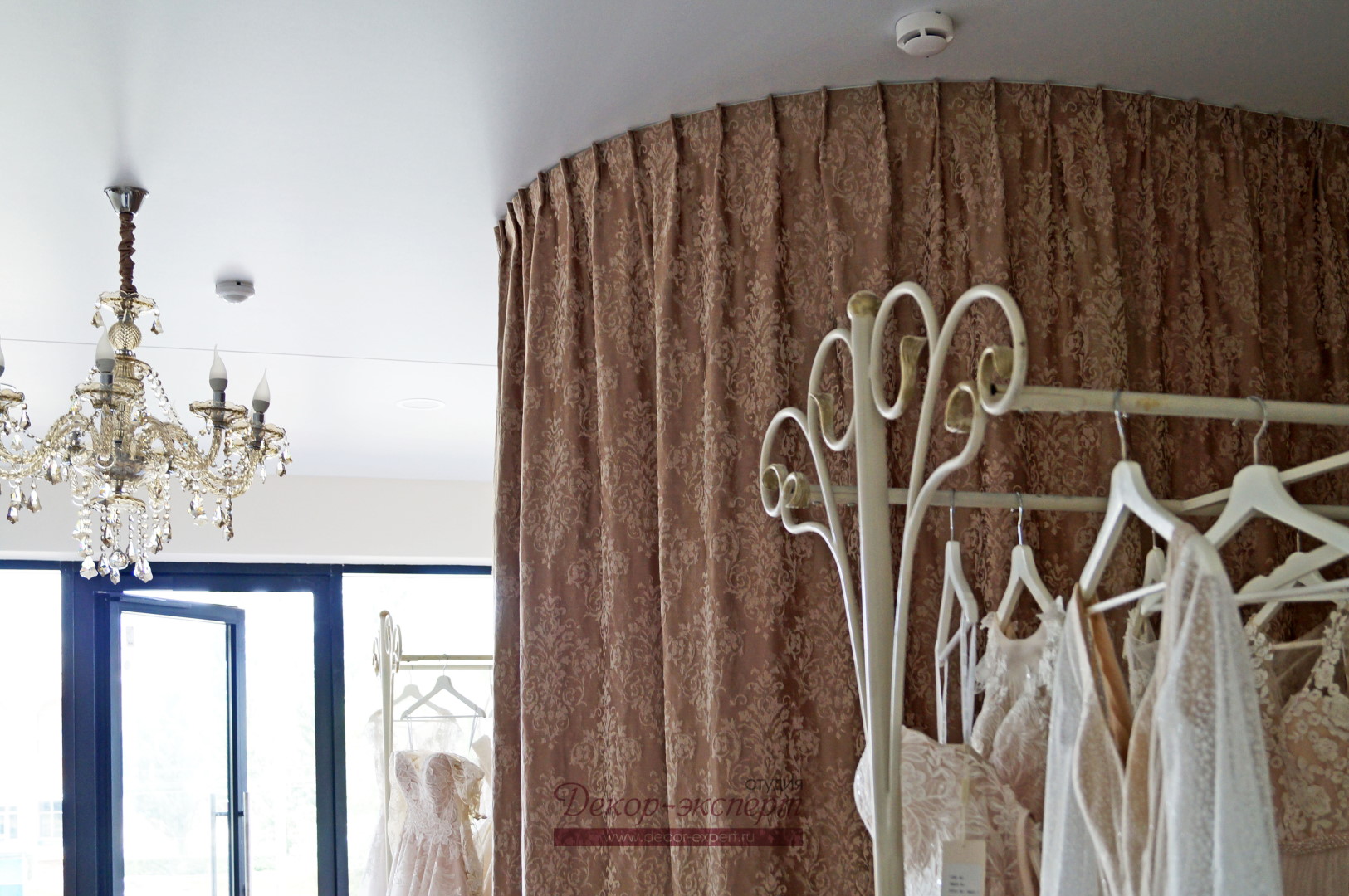 Шторки для примерочной в салоне свадебных платьев на изогнутом карнизе под натяжным потолком.