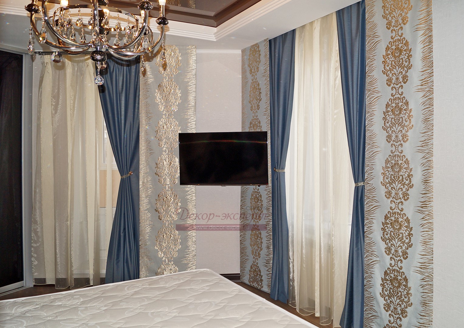 Вариант ассиметричной комбинации трёх японских штор и трёх портьер для двух окон в спальне. Золотистый цвет дамасков на панелях перекликается с рефлексами подвесок люстры.