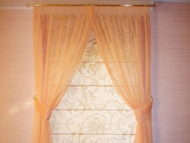 Симетричная комбинация римской шторы и тюля на окне гостиной.