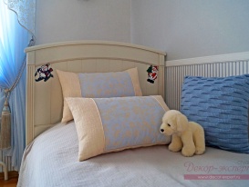 Две декоративные подушки с кантом и третья с объёмной вязкой на кровати в комнате девочки.